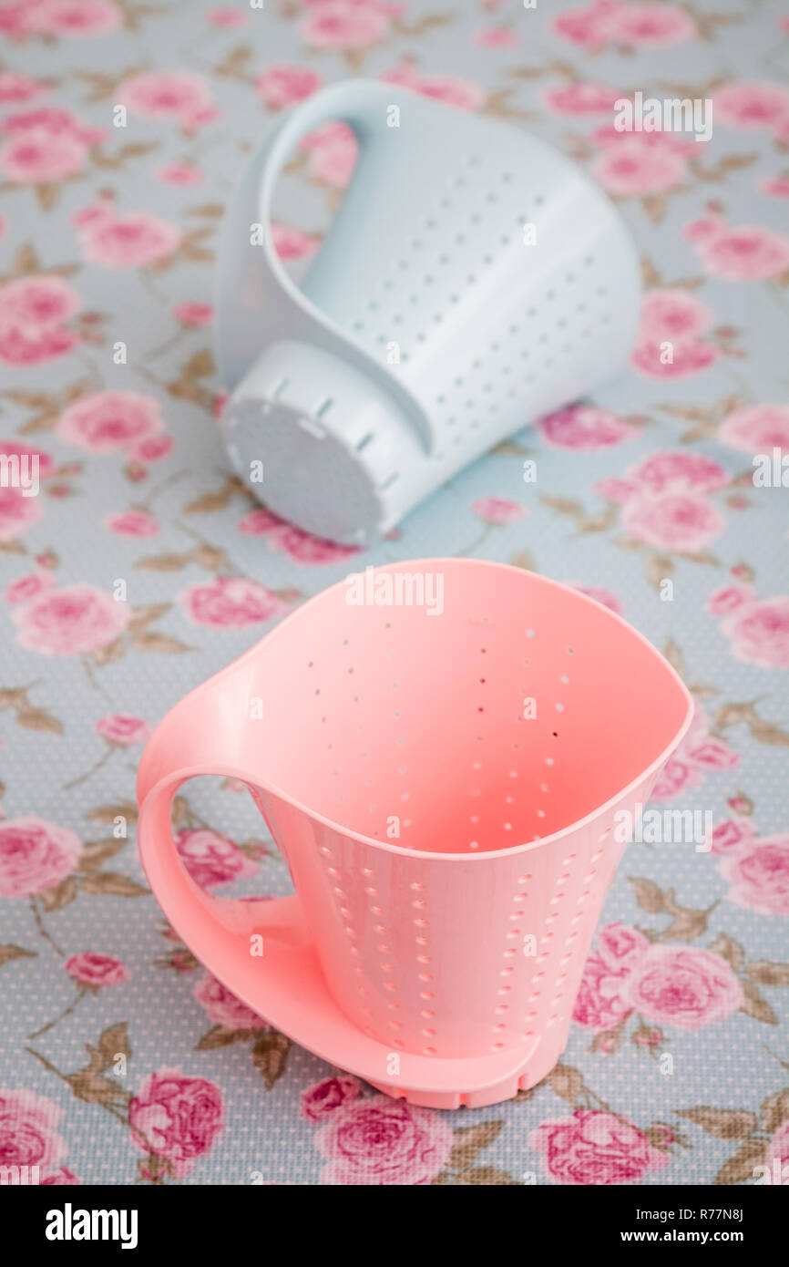 Colorful Plastic Colanders with Handles on Floral Pattern Stock Photo