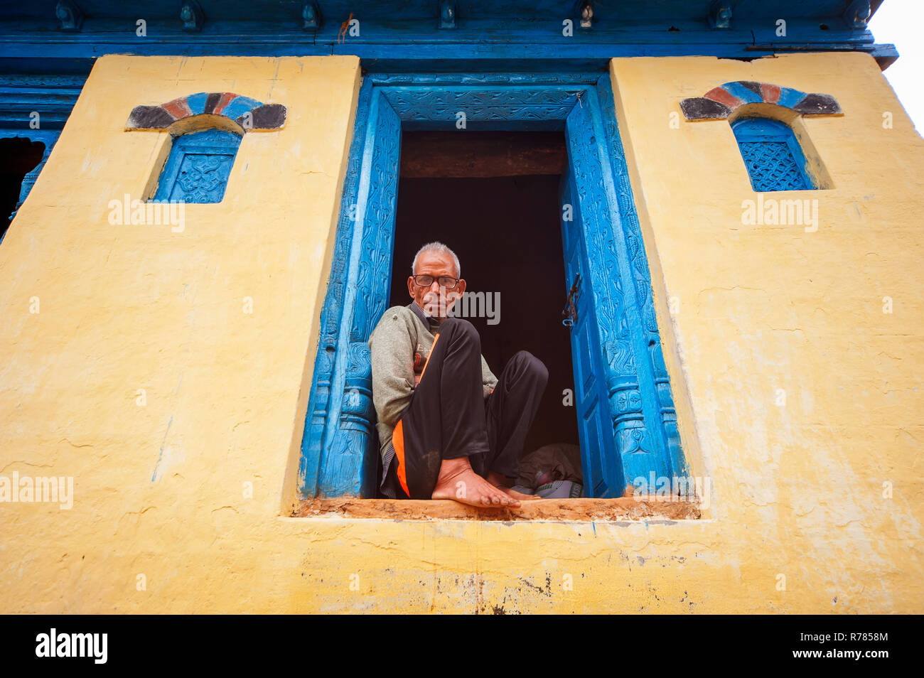 Old indian man sitting at the door of his kumaoni house at Sanouli village, Uttarakhand, India Stock Photo