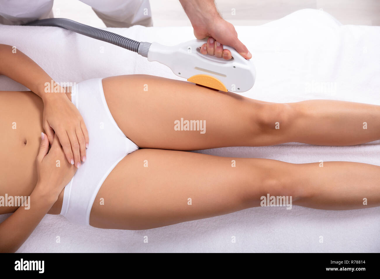 Close-up Of Beautician Hand Using Laser Machine On Customer's Leg In Spa Stock Photo