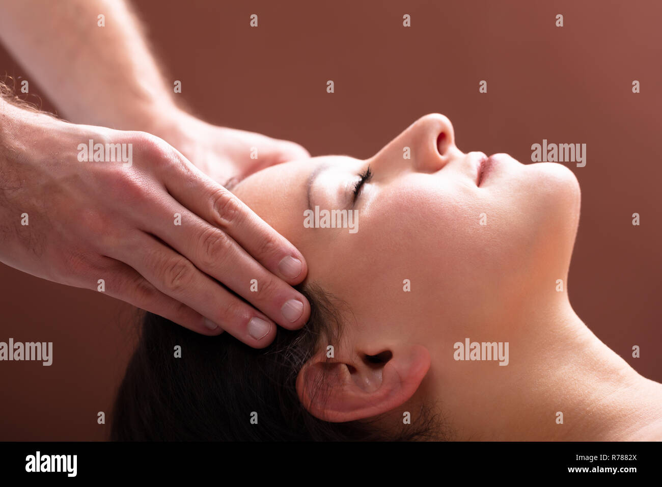 Close-up Of A Therapist Hand Massaging Young Woman's Head Stock Photo