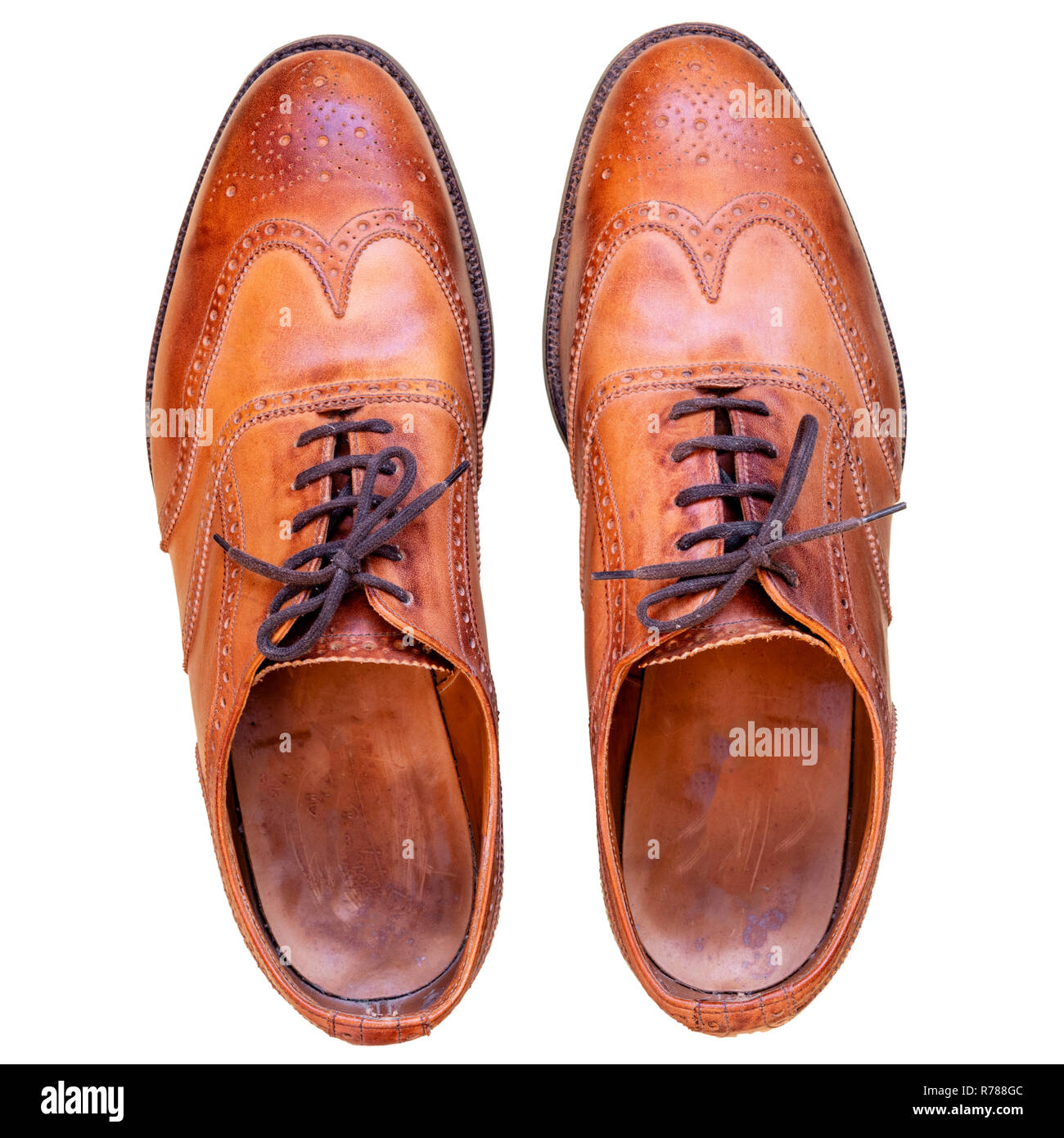 Tan brogues cut out on a white background. Mens used brown leather shoes shot from above. Stock Photo