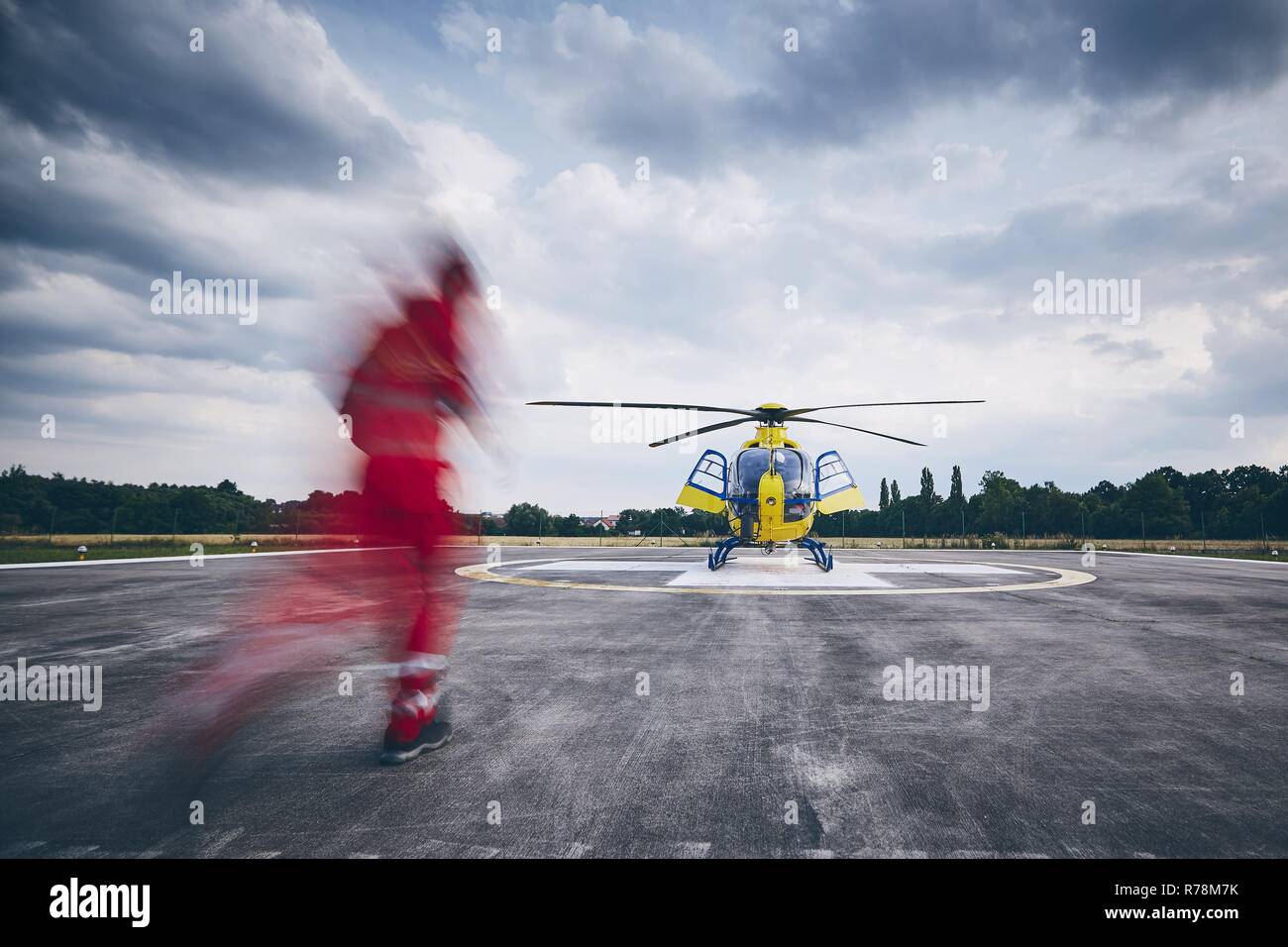 Alarm for helicopter emergency medical service. Paramedic running to helicopter on heliport. Stock Photo