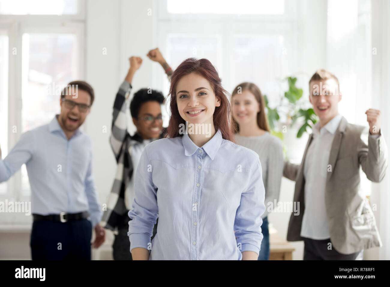 Portrait of successful female employee with excited colleagues a Stock Photo