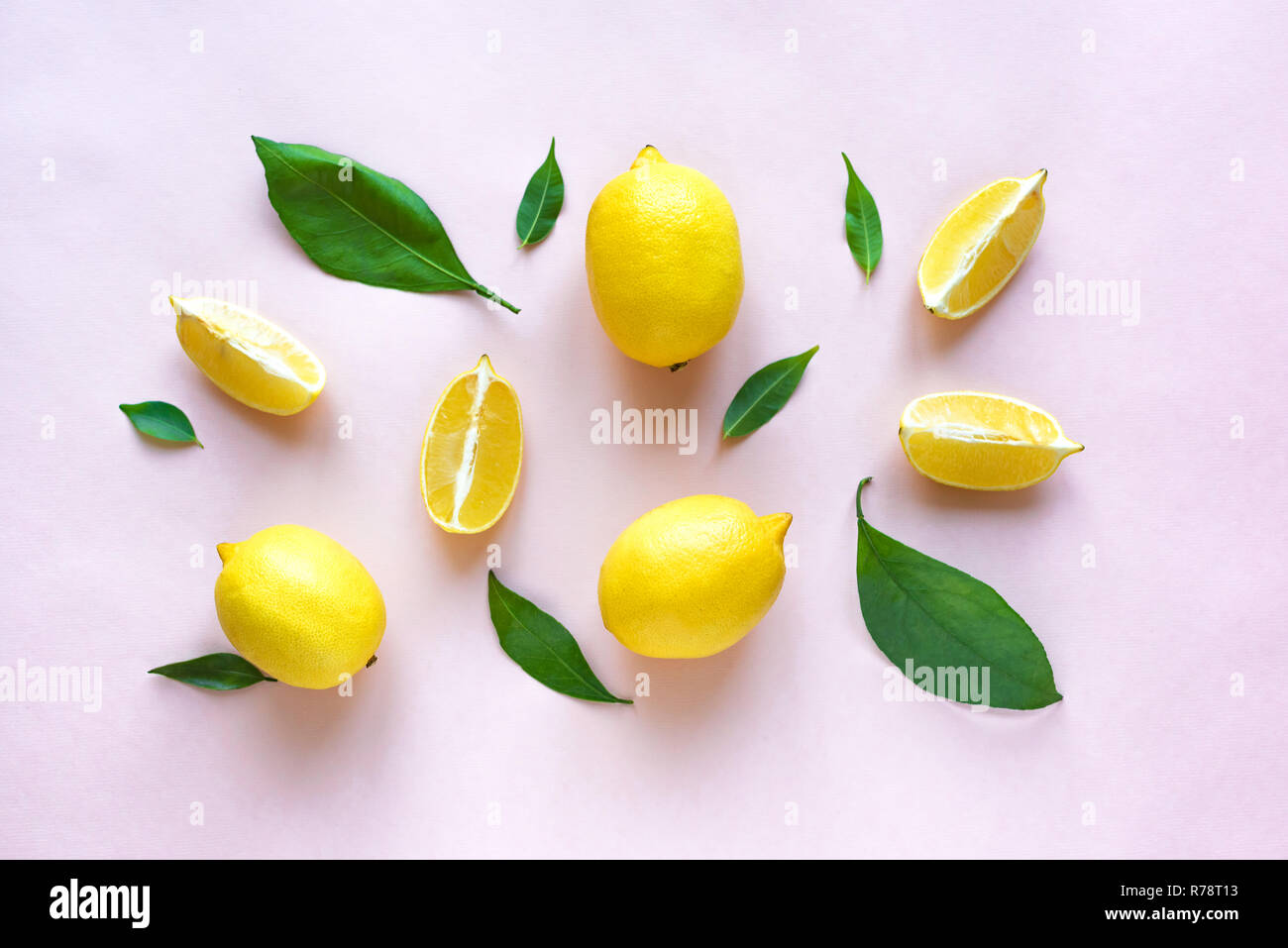 Lemons with green leaves on pink pastel background, top view, flat lay. Organic fresh citrus fruits lemons, minimal conceptual flat lay. Stock Photo