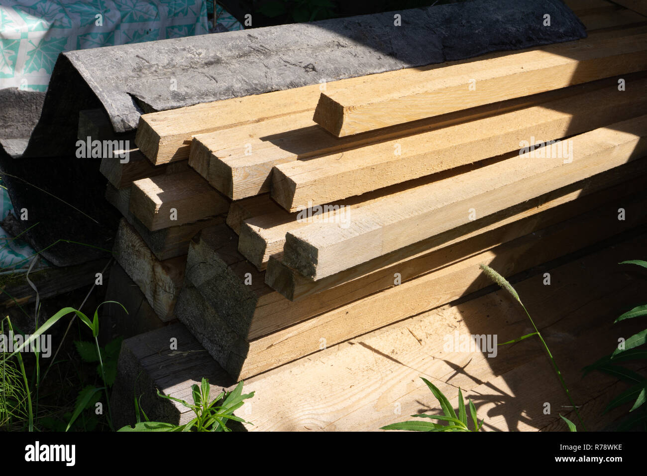 Stack of natural brown uneven rough wooden boards on building site