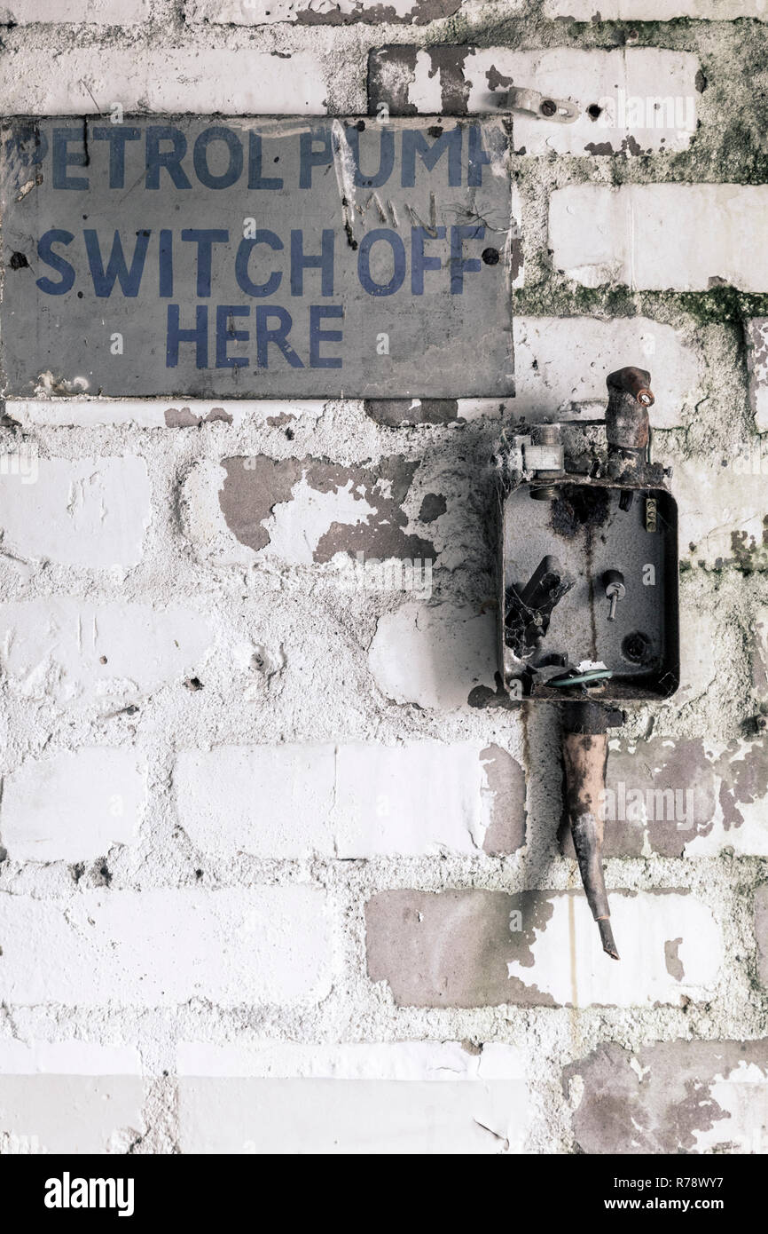 Old electricity switch box on a wall, with a sign saying "petrol pump