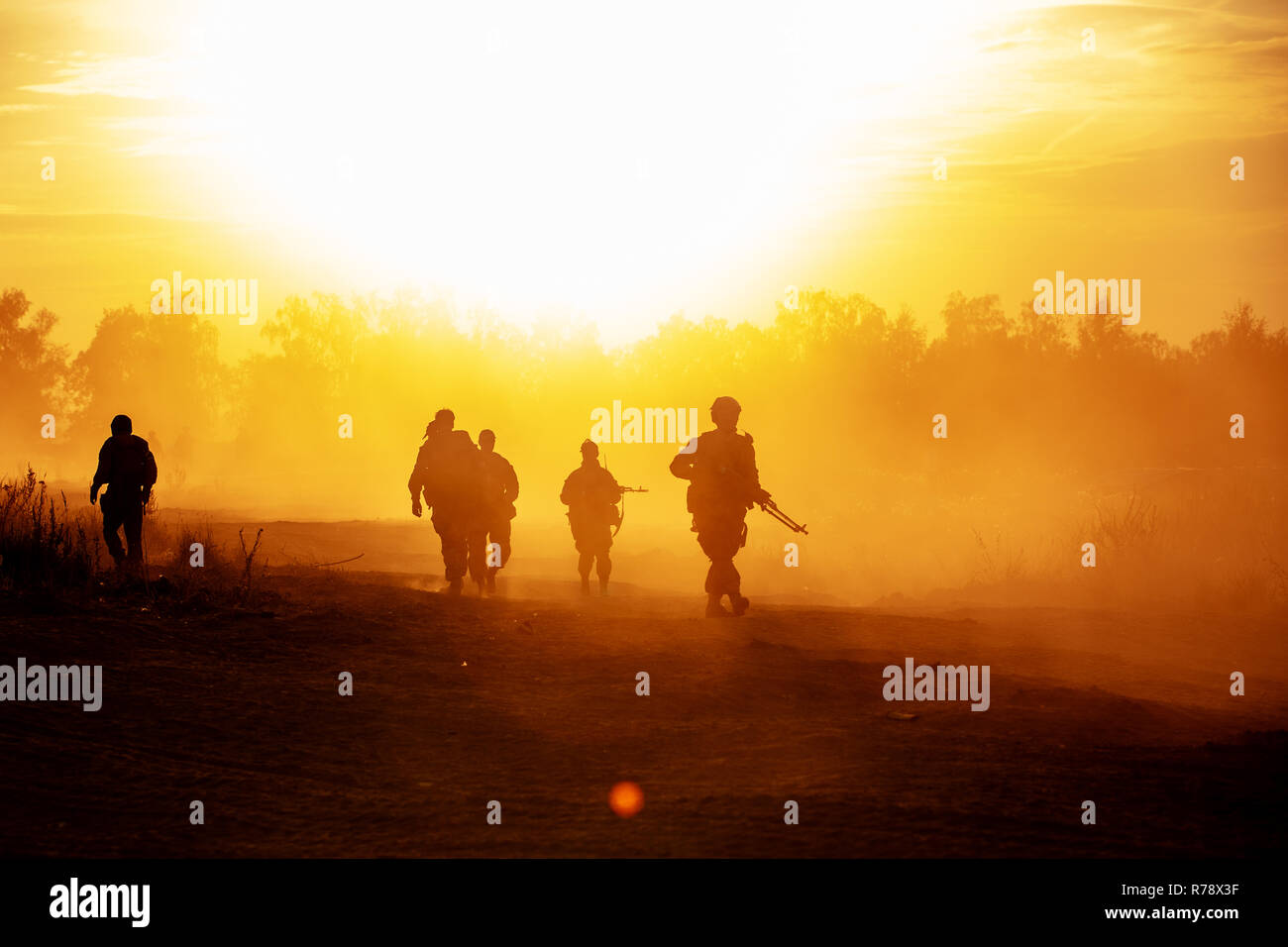 silhouette action soldiers walking hold weapons the background is smoke and sunset and white balance ship effect dark art style Stock Photo