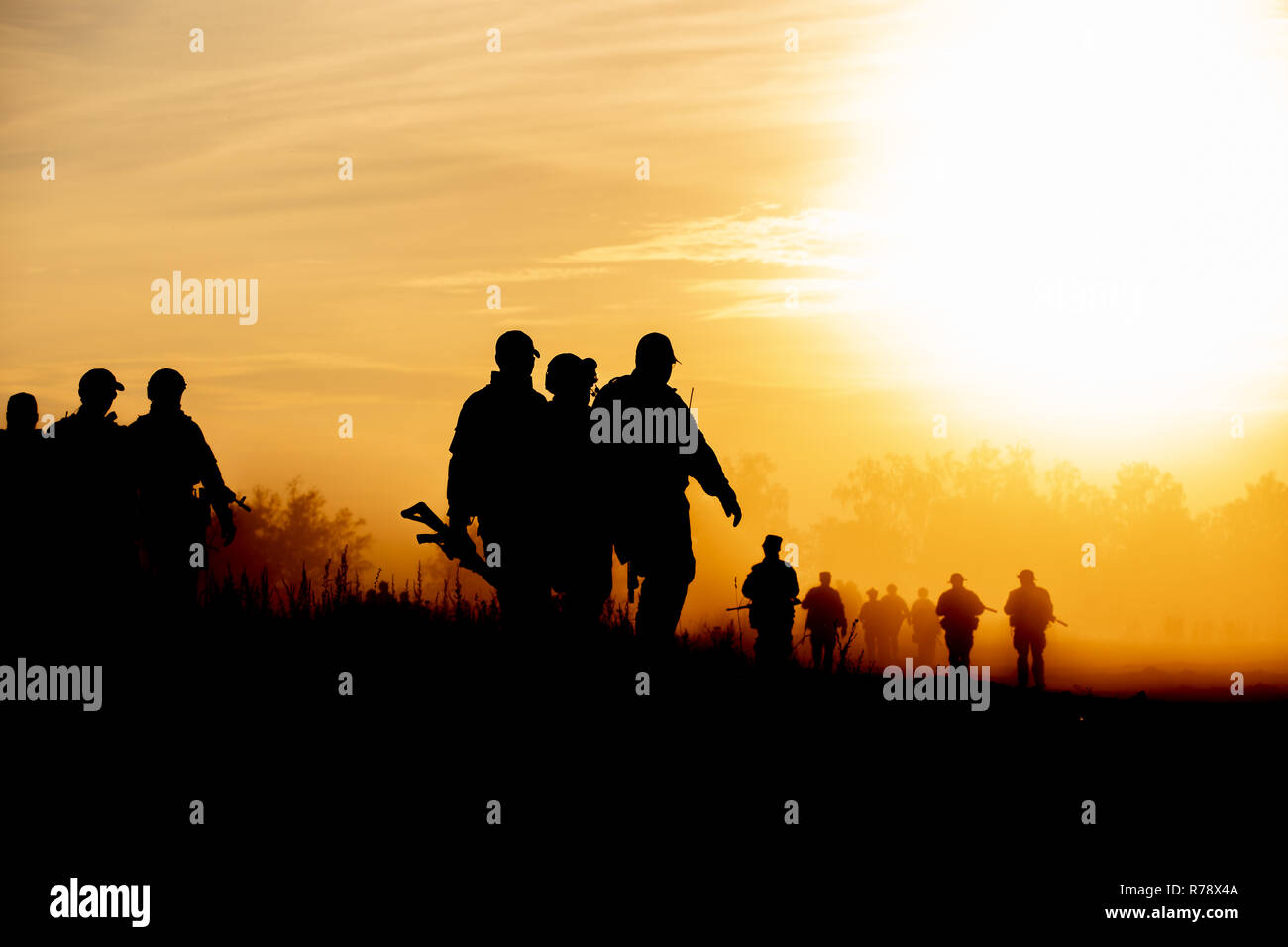 silhouette action soldiers walking hold weapons the background is smoke and sunset and white balance ship effect dark art style Stock Photo