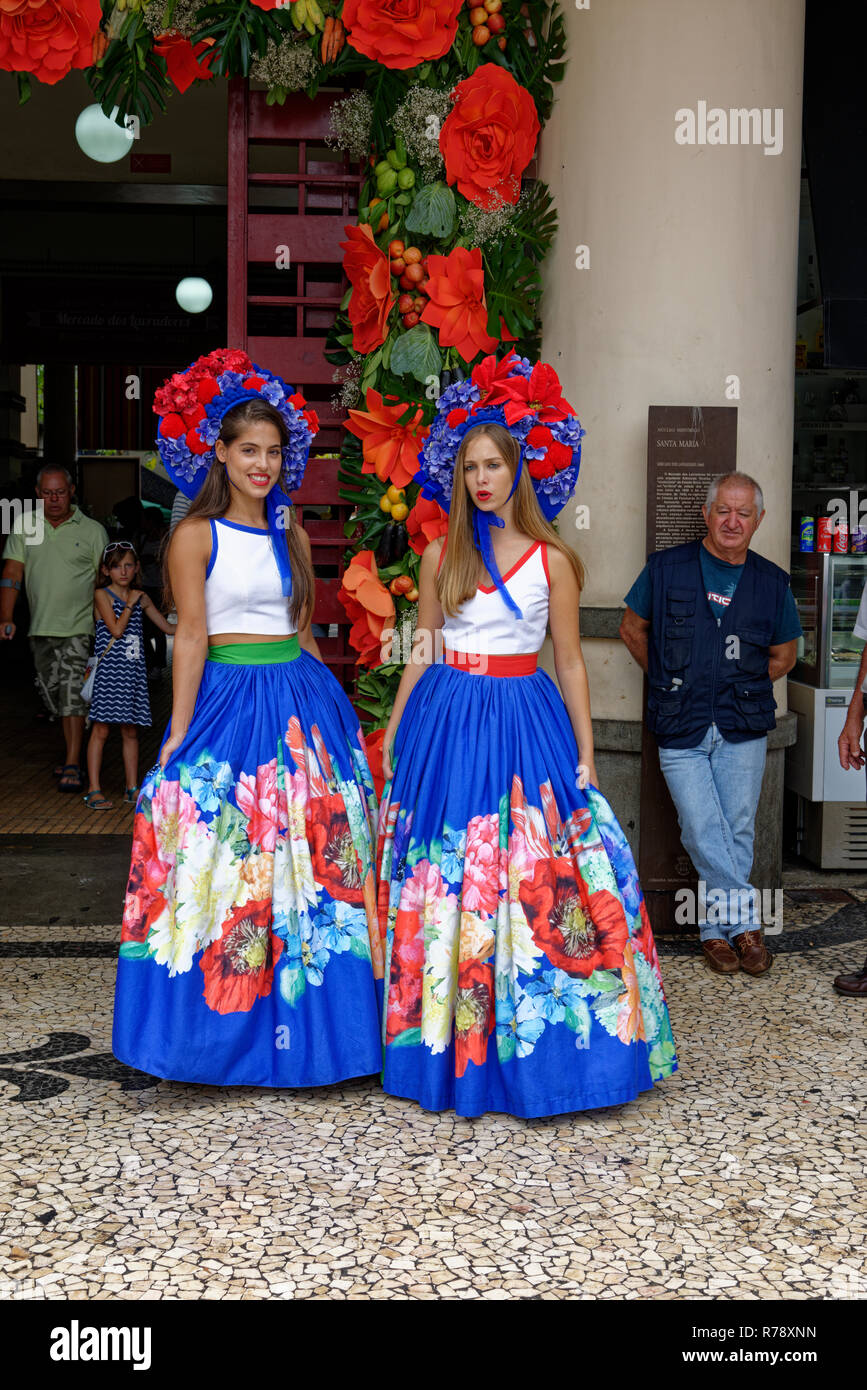 Two young women in colourful versions of Tradional Costume with large pleated skirts and flowery headpieces in the city of Funchal on Madeira Stock Photo