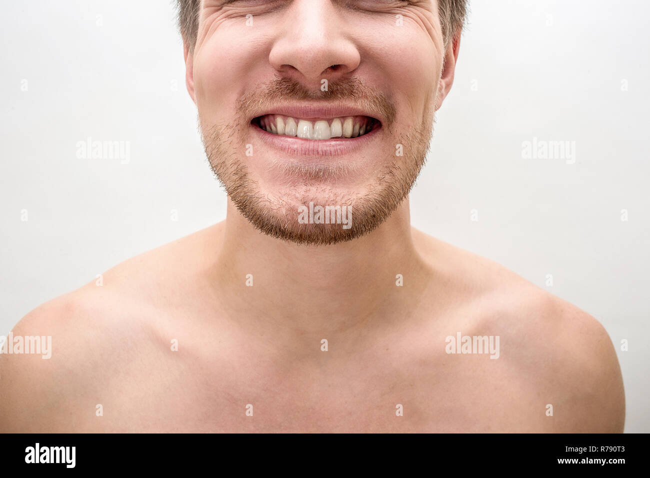 Cut virew of young man smiling. He shows healthy white teeth. Isolated on white baclground. Close up. Stock Photo