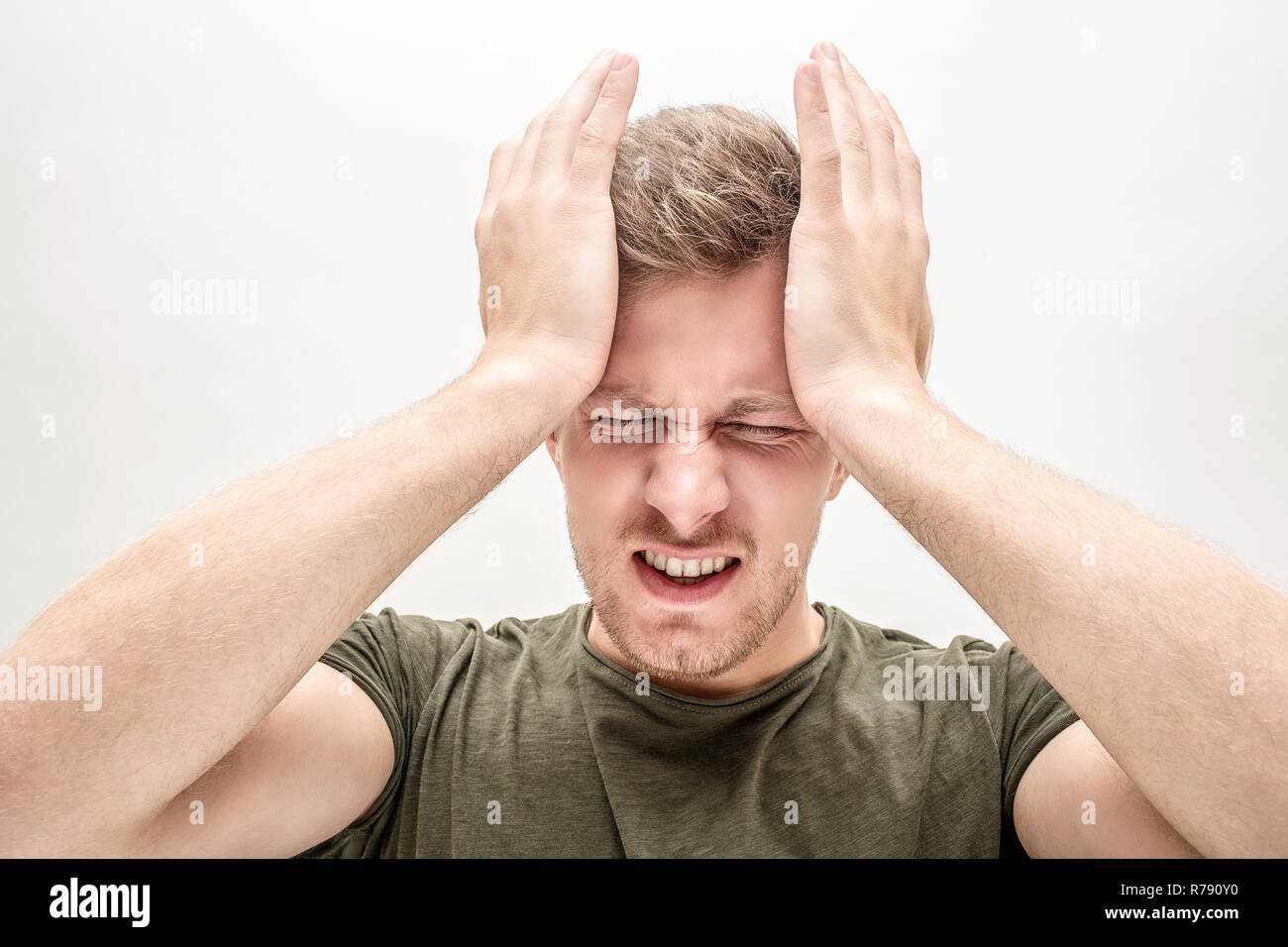 Handsome young man has headache. He suffer. Guy hold hands on forehead. Isolated on white background. Stock Photo