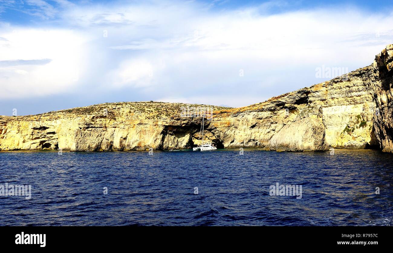 Comino, Malta - 12th October 2018:Catamaran at anchor below the cliffs of Comino Stock Photo
