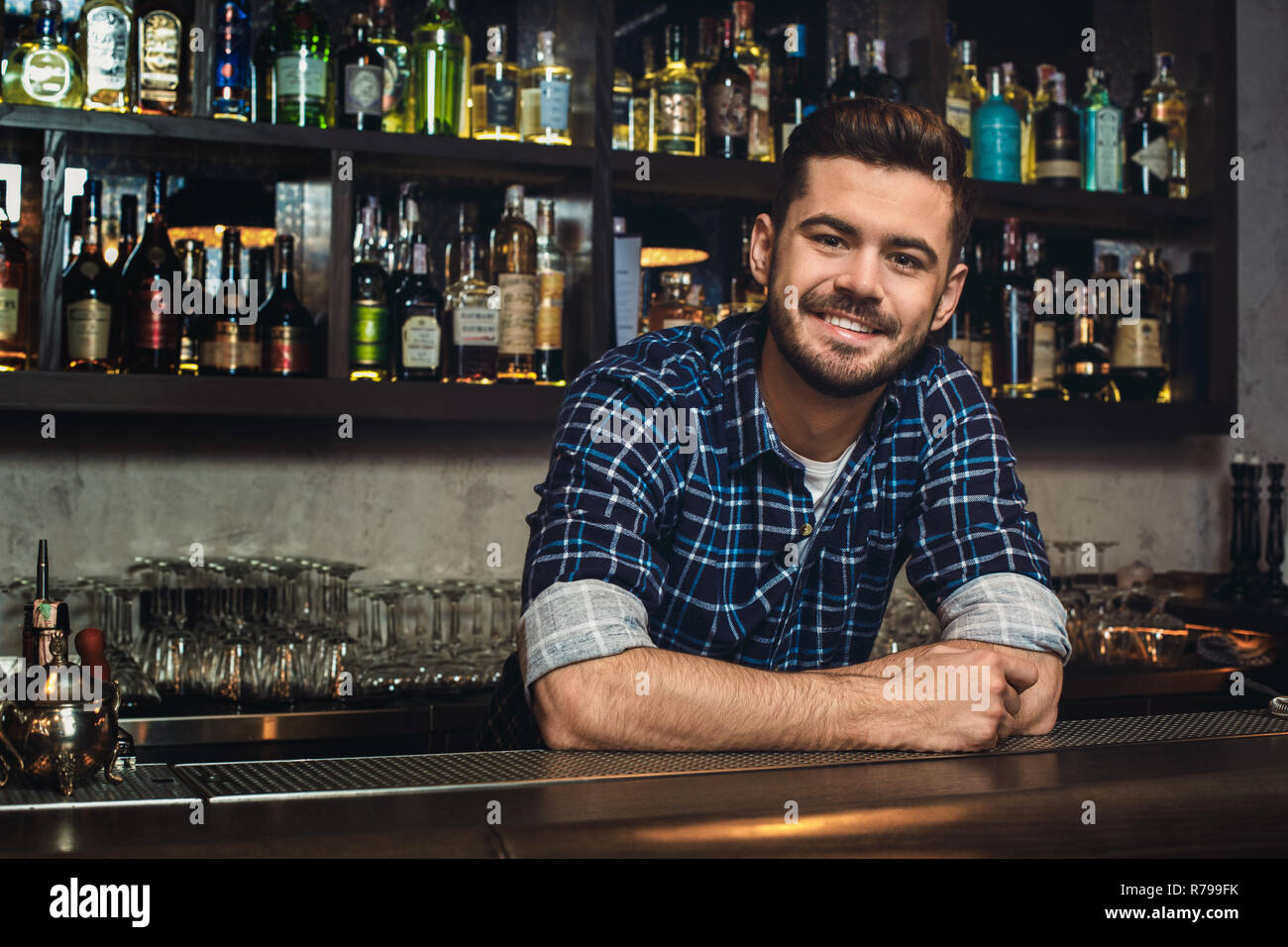 Young bartender leaning at bar counter smiling cheerful Stock Photo