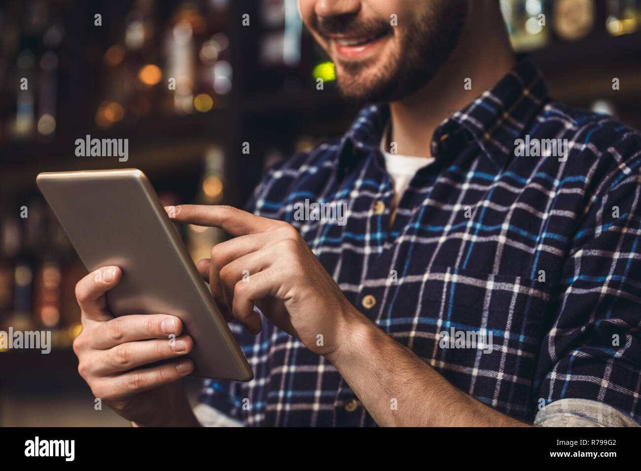 Young bartender standing at bar browsing digital tablet happy close-up Stock Photo