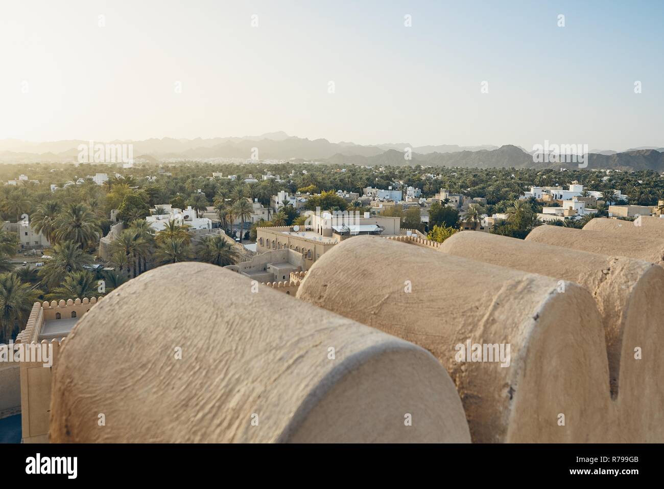 City against mountain range at idyllic sunset. Nizwa in Sultanate of Oman. Stock Photo