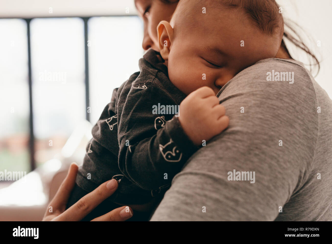 Side view of a mother carrying her sleeping baby. Baby sleeping with