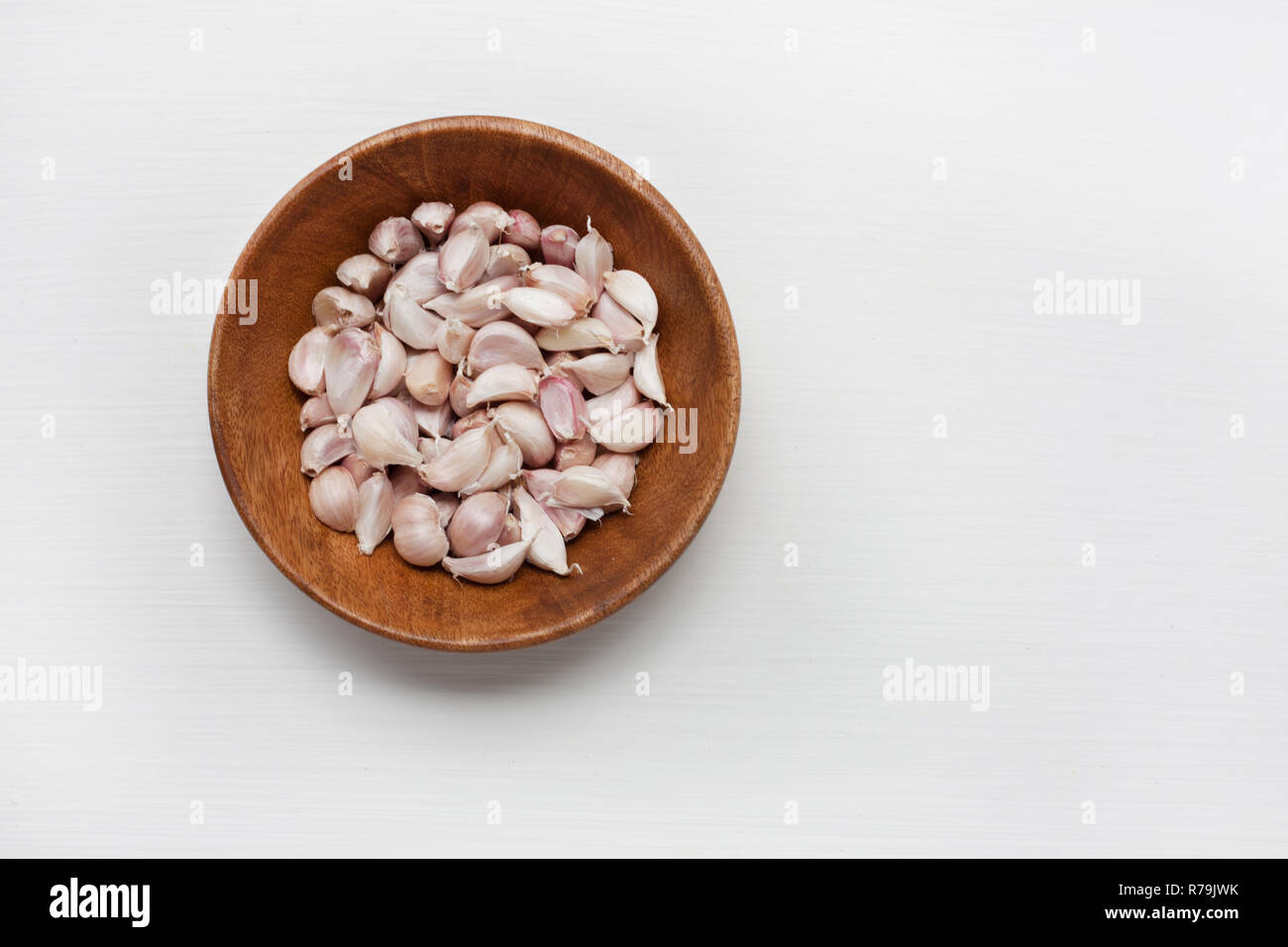 Garlic in wooden bowl isolated on white Stock Photo - Alamy