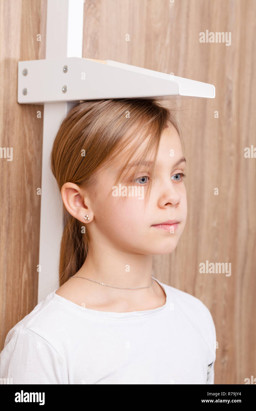 Portrait of cute preteen girl during stature measurement  with stadiometer - child check-up concept Stock Photo
