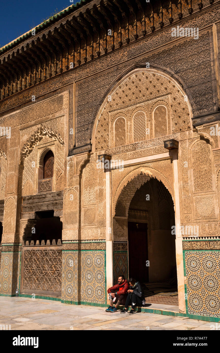 Morocco, Fes, Fes el Bali, Medina, Talaa Seghira, Medersa Bou Inania, young tourists sat in door Stock Photo