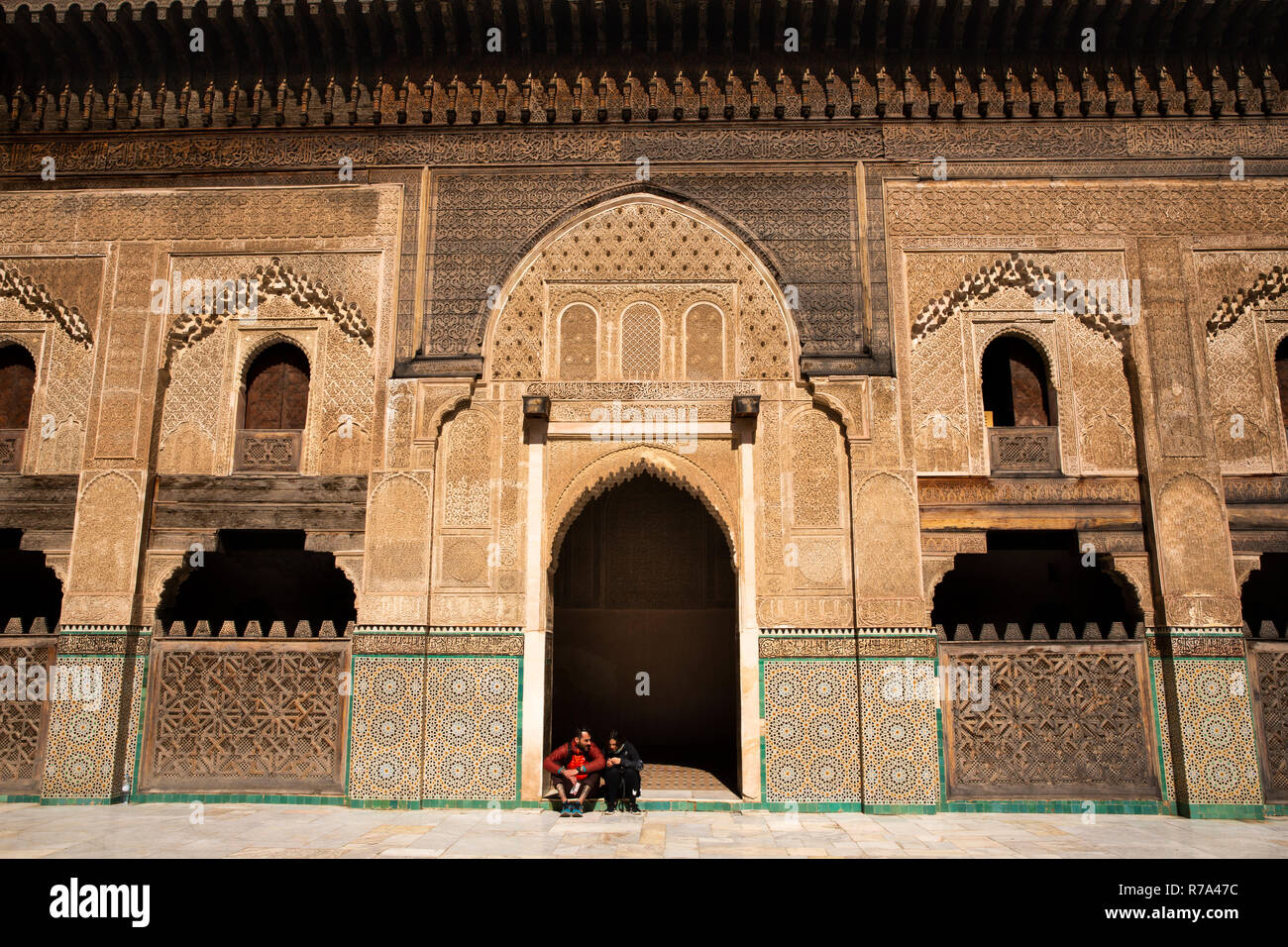 Morocco, Fes, Fes el Bali, Medina, Talaa Seghira, Medersa Bou Inania, young tourists sat in door Stock Photo