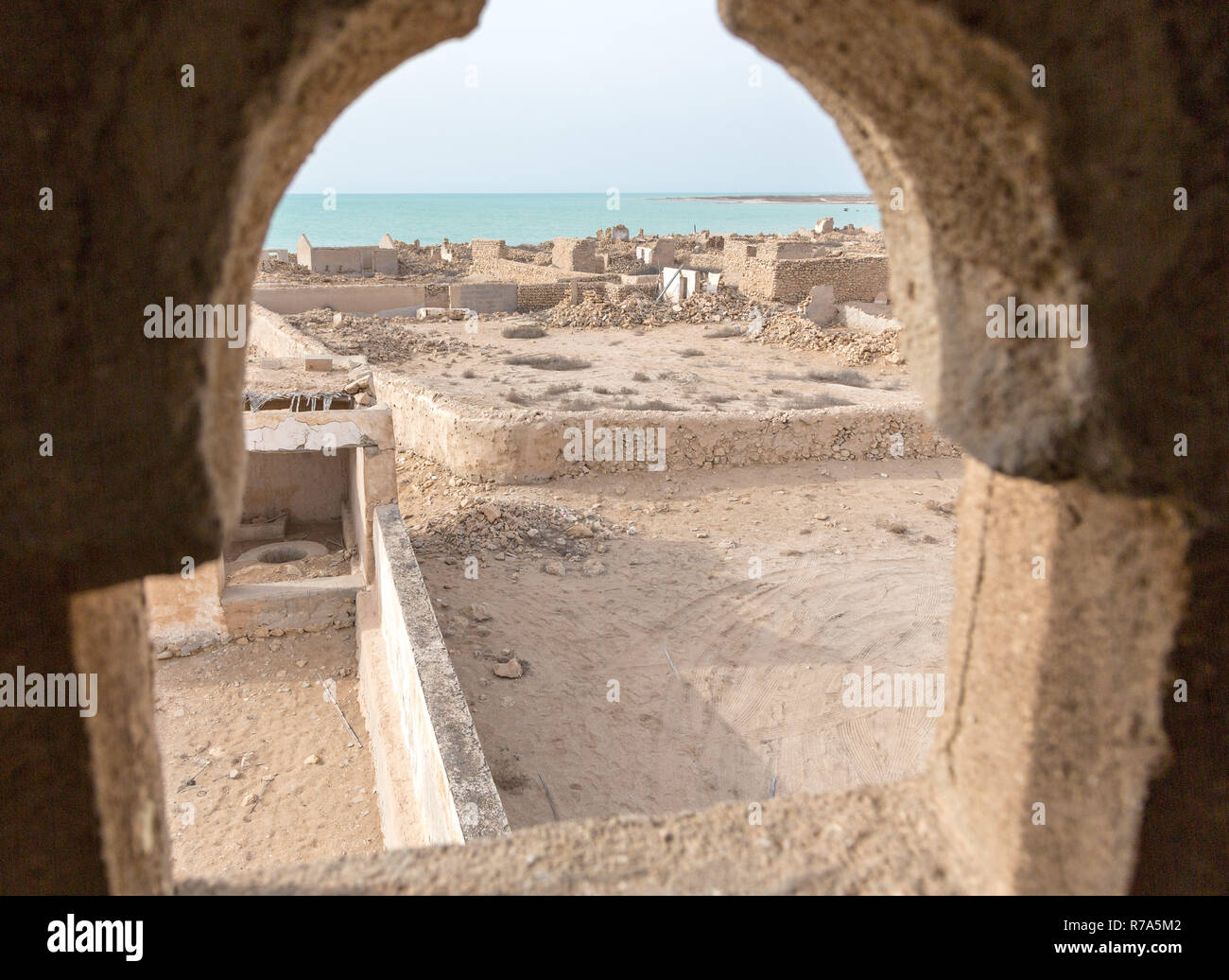 Ruined ancient Arab pearling, fishing town Al Jumail, Qatar. Desert at coast of Persian Gulf. Lost village. A view out of minaret's window to the sea Stock Photo