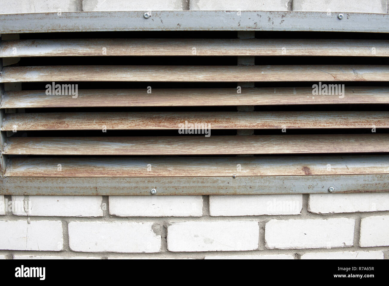 A brick wall with a rusty iron grille Stock Photo