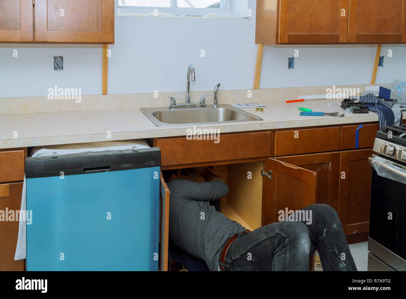 Man repairing sink pipe in the kitchen plumber fitting pipes  Stock Photo