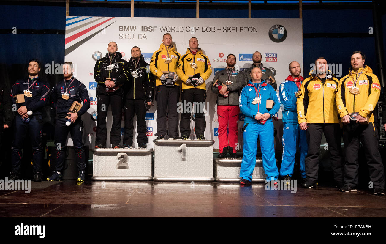 Sigulda, Latvia. 08th Dec, 2018. Bob: World Cup, two-man bobsleigh, men:  The winners Francesco Friedrich and Alexander Schüller from Germany are on  the podium next to the runners-up Oskars Kibermanis and Matiss