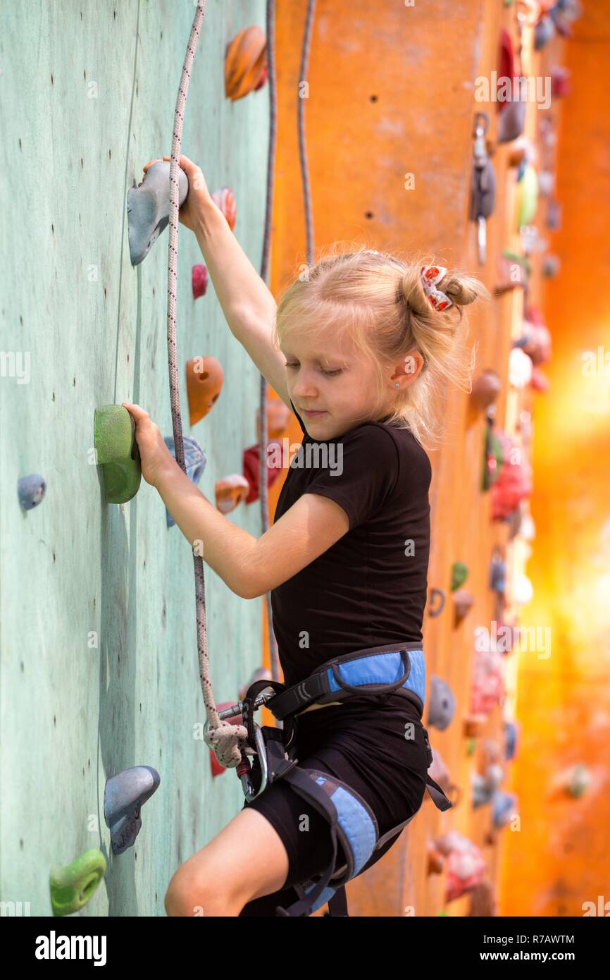 bouldering, little girl climbing up the wall Stock Photo
