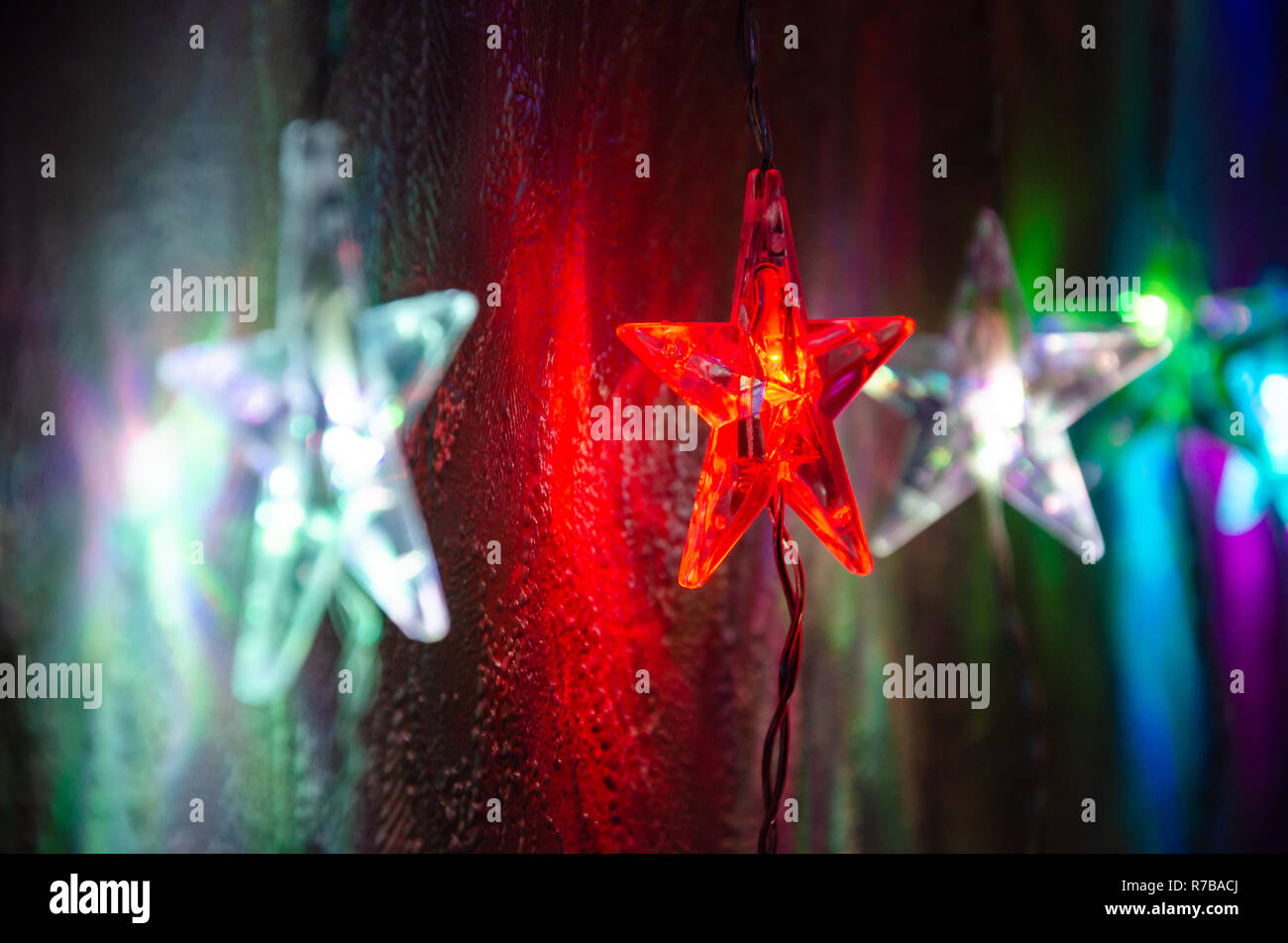 Colourful, festive star shaped Christmas lights glowing in the dark. Stock Photo