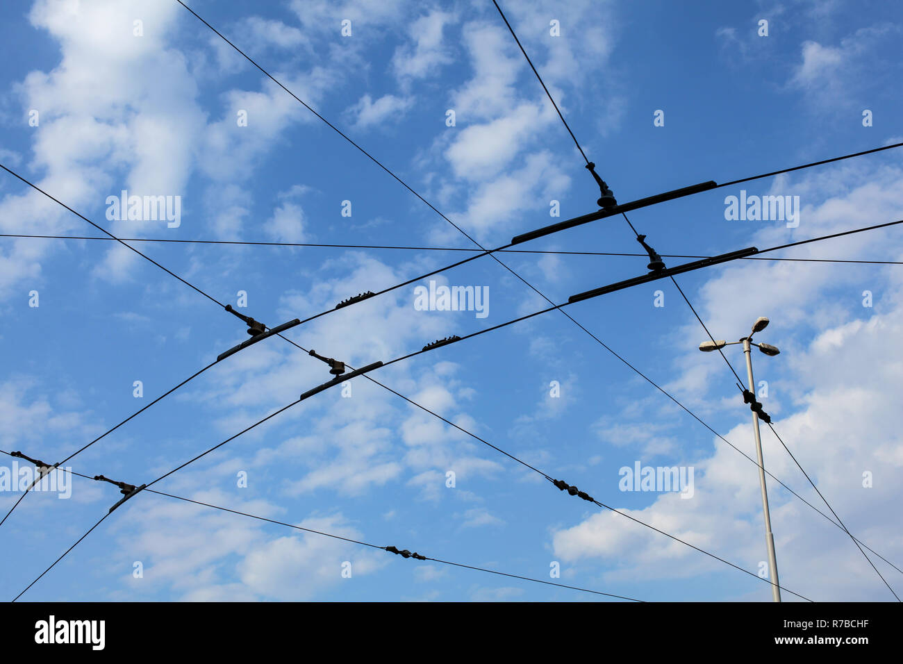 Streetcar / tram trolley overhead electric lines against blue sky. Stock Photo