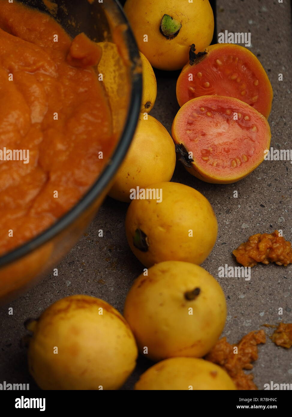 Guava fruit being processed in a country kitchen. Fresh, wild harvest fruit. Pink and yellow guava. Stock Photo