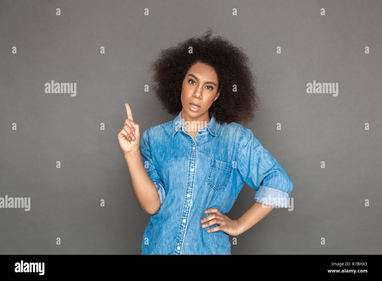 Freestyle. Mulatto woman standing isolated on grey pointing up looking camera  sassy Stock Photo - Alamy