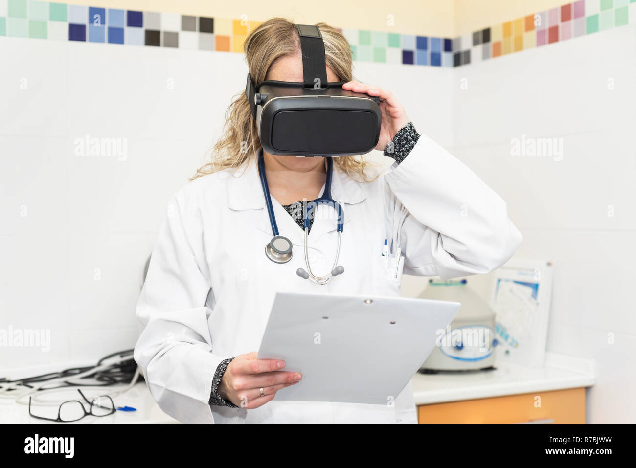 Scientist with clipboard using virtual reality glasses for research in laboratory Stock Photo