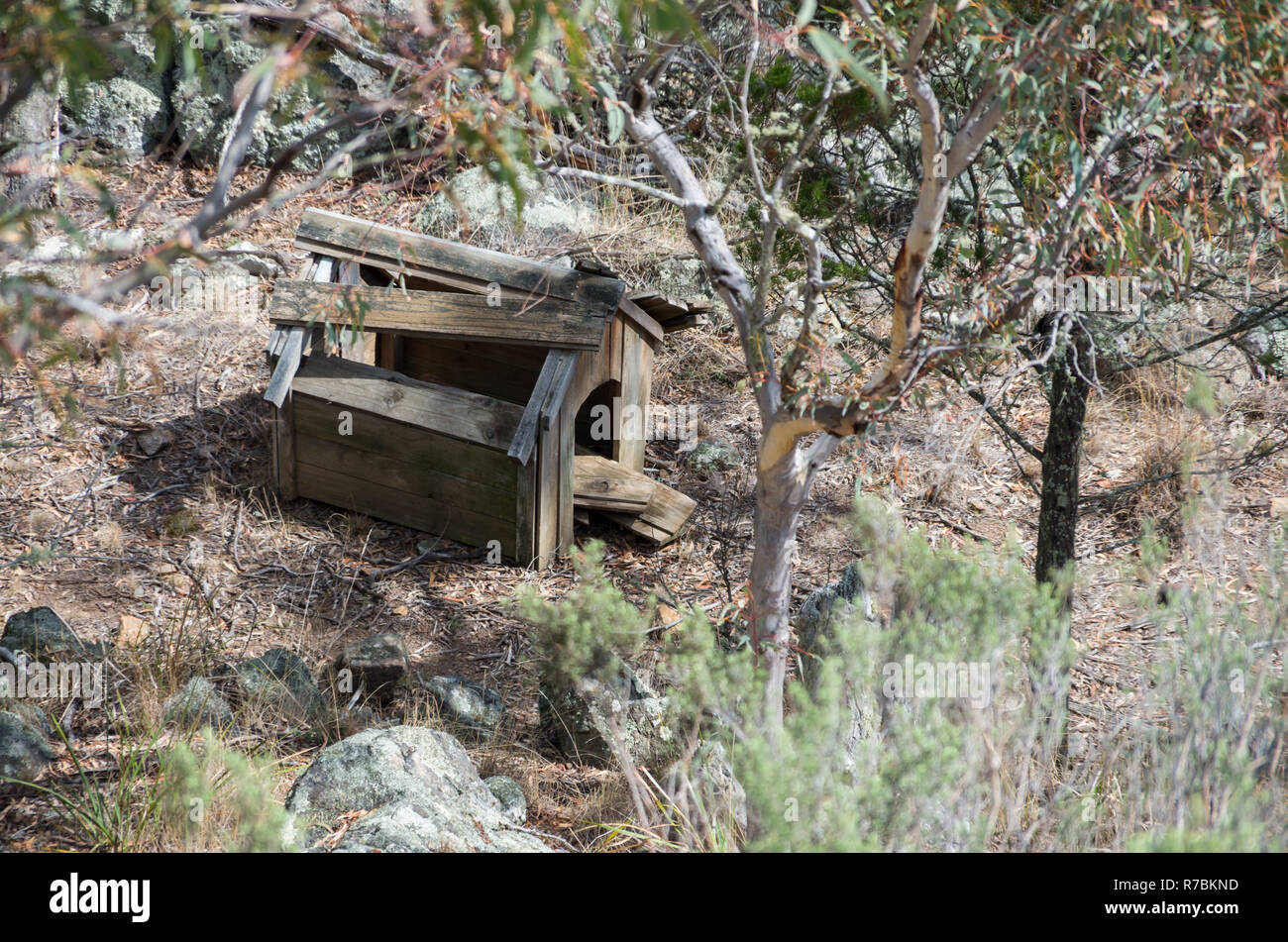 Old broken abandoned dog house falling apart in Australian bush land