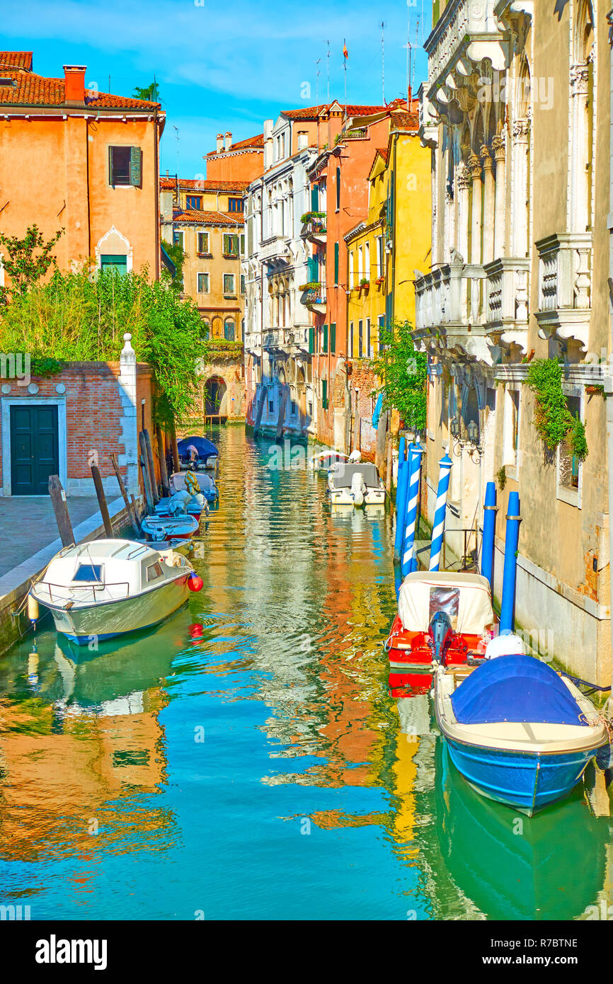 Picturesque side canal with moored motorboats in Venice, Italy Stock Photo