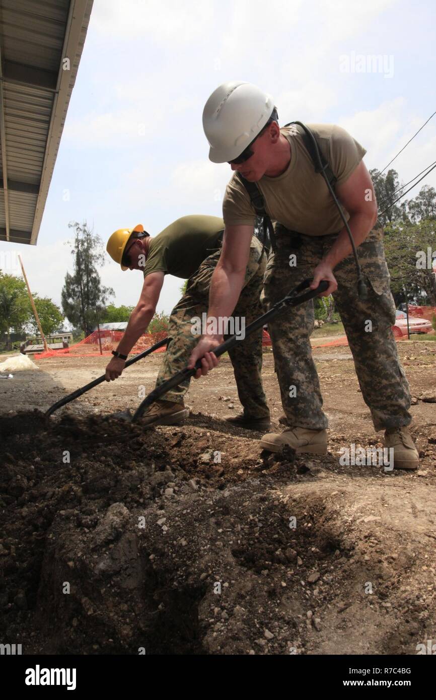 U.S. Army Sgt. Curtis Pippin, with the 128th Medical Detachment, Georgia National Guard, and Marine Cpl. Justin Dorris, with Bridge Company C, 6th Engineer Support Battalion, based out of Millington, Tennessee, cover water pipes coming from a newly constructed emergency room during Beyond the Horizon 2017, in Belmopan, Belize, May 12, 2017. BTH 2017 is a U.S. Southern Command-sponsored, Army South-led exercise designed to provide humanitarian and engineering services to communities in need, demonstrating U.S. support for Belize. Stock Photo