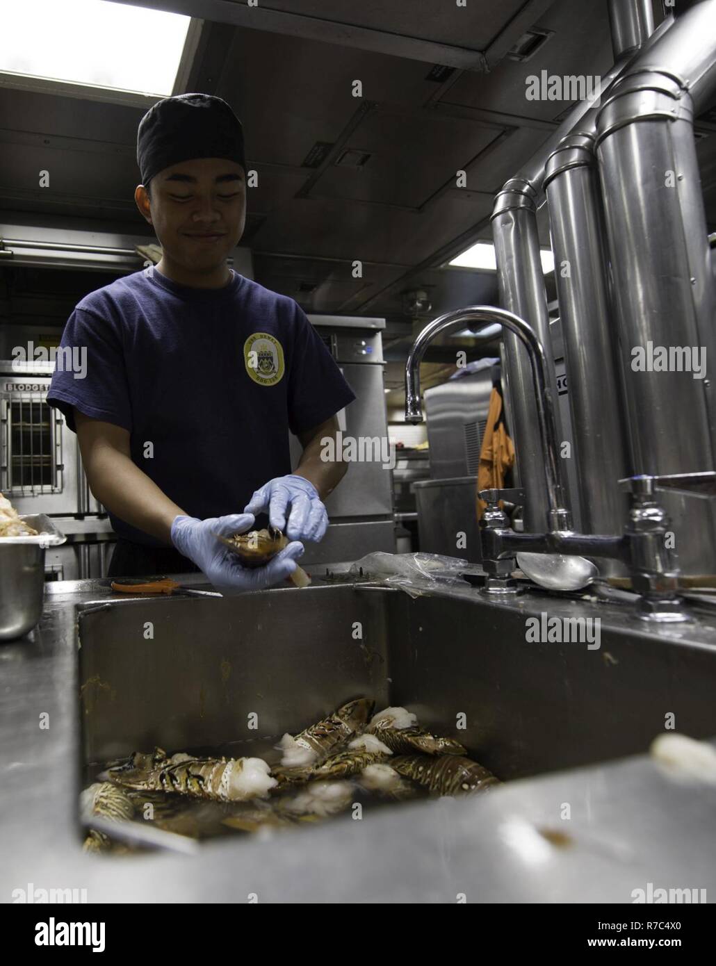 SOUTH CHINA SEA(May 14, 2017)   Christianjo Bejec, a native of the Philippines, prepares lobster in the galley aboard the Arleigh Burke-class guided-missile destroyer USS Dewey (DDG 105).  Dewey is part of the Sterett-Dewey Surface Action Group and is the third deploying group operating under the command and control construct called 3rd Fleet Forward.  The U.S. 3rd Fleet operating forward offers additional options to the Pacific Fleet commander by leveraging the capabilities of 3rd and 7th Fleets. Stock Photo