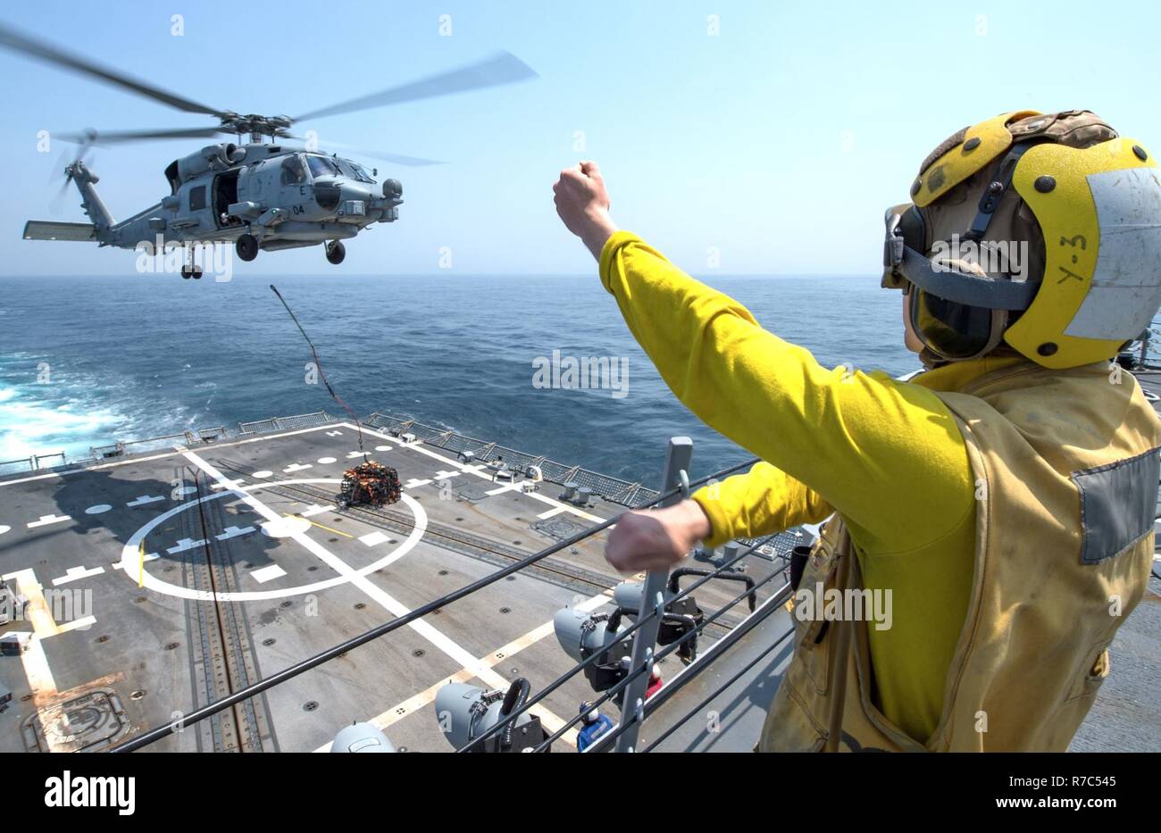 WATERS SOUTH OF JAPAN (May 12, 2017) Electronics Technician 3rd Class Jonathan Hill guides an MH-60R Sea Hawk helicopter assigned to the “Warlords” of Helicopter Maritime Strike Squadron (HSM) 51 during a vertical replenishment training exercise aboard the Arleigh Burke-class guided-missile destroyer USS McCampbell (DDG 85). The ship is on patrol in the U.S. 7th Fleet area of operations in support of security and stability in the Indo-Asia-Pacific region. Stock Photo