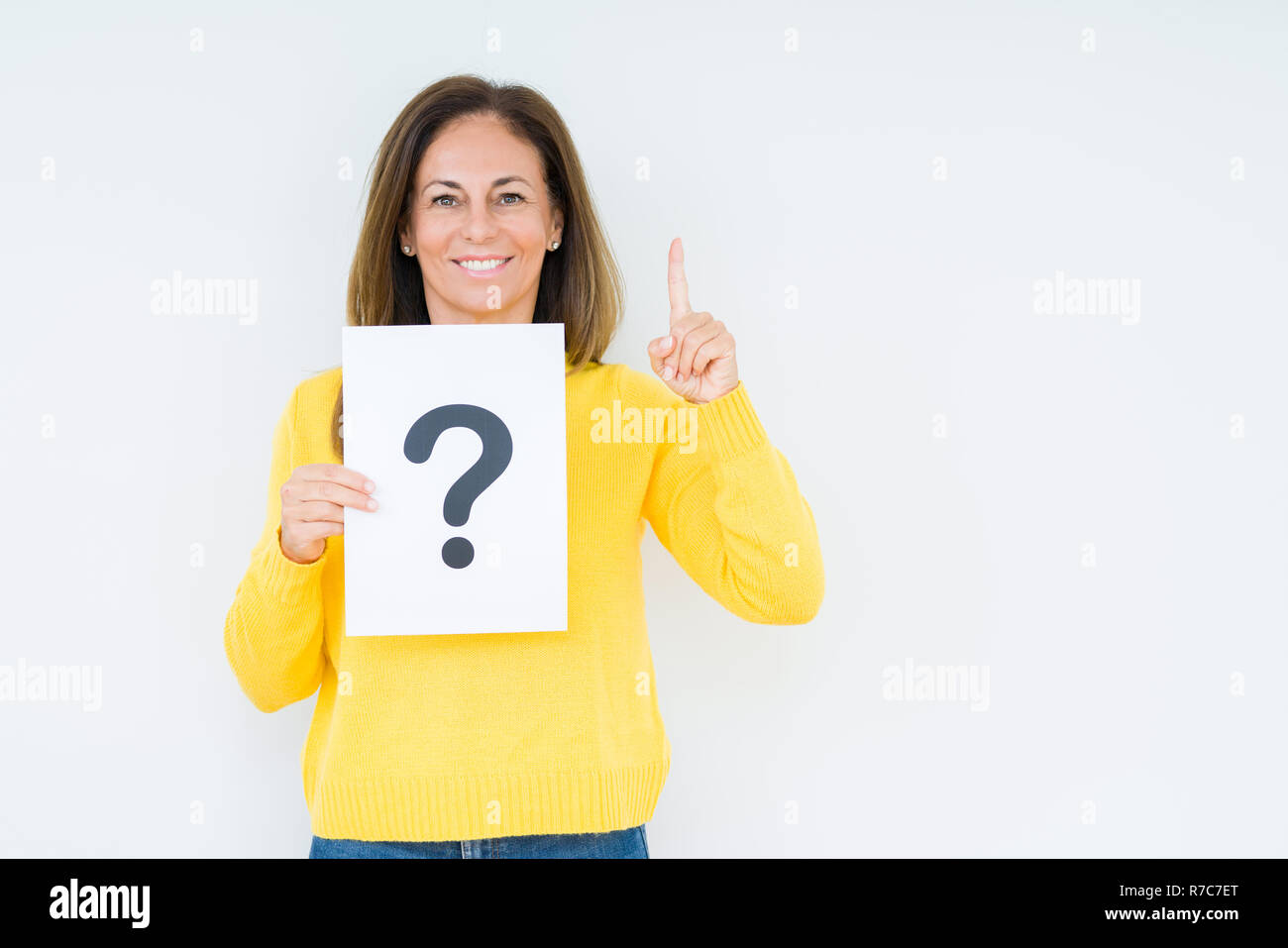 Middle age woman thinking and holding paper with question mark symbol ...