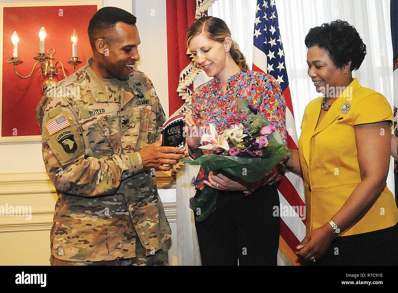 Col. Adam W. Butler, U.S. Army Garrison commander, presents the 2017 Heroes at Home award to Maria Fowler as Myra Williams, wife of Maj. Gen. Darrell K. Williams, CASCOM and Fort Lee commanding general, watches during the Heroes at Home Military Spouse Appreciation Awards event May 5 at the Lee Club.  Fowler was selected among 16 spouses representing all services within the central Virginia region. Stock Photo