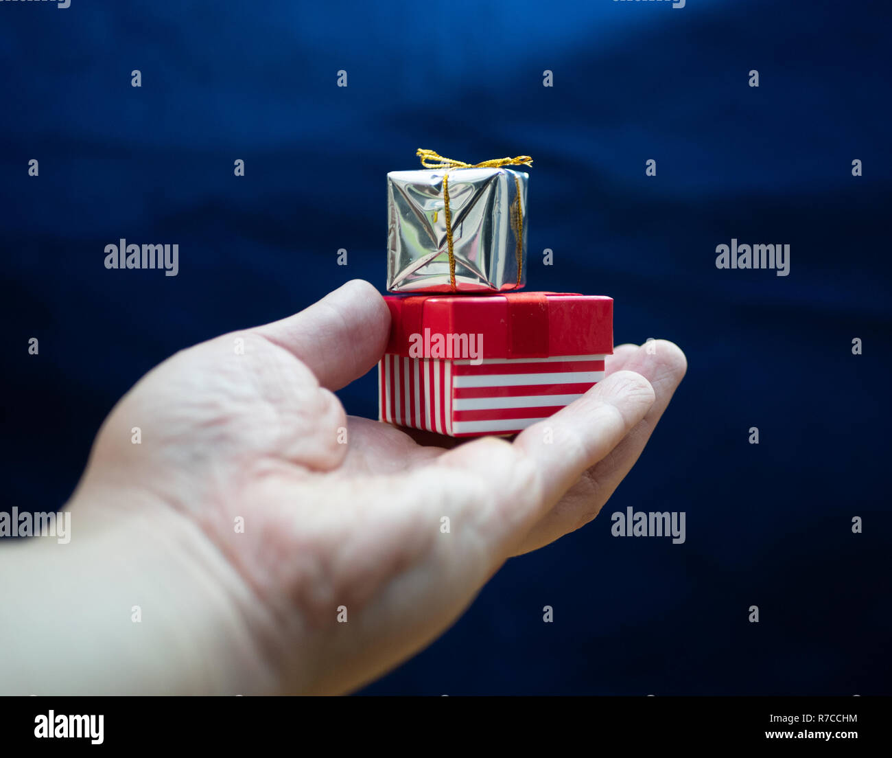 streched hand with two small gift boxes on blue background Stock Photo