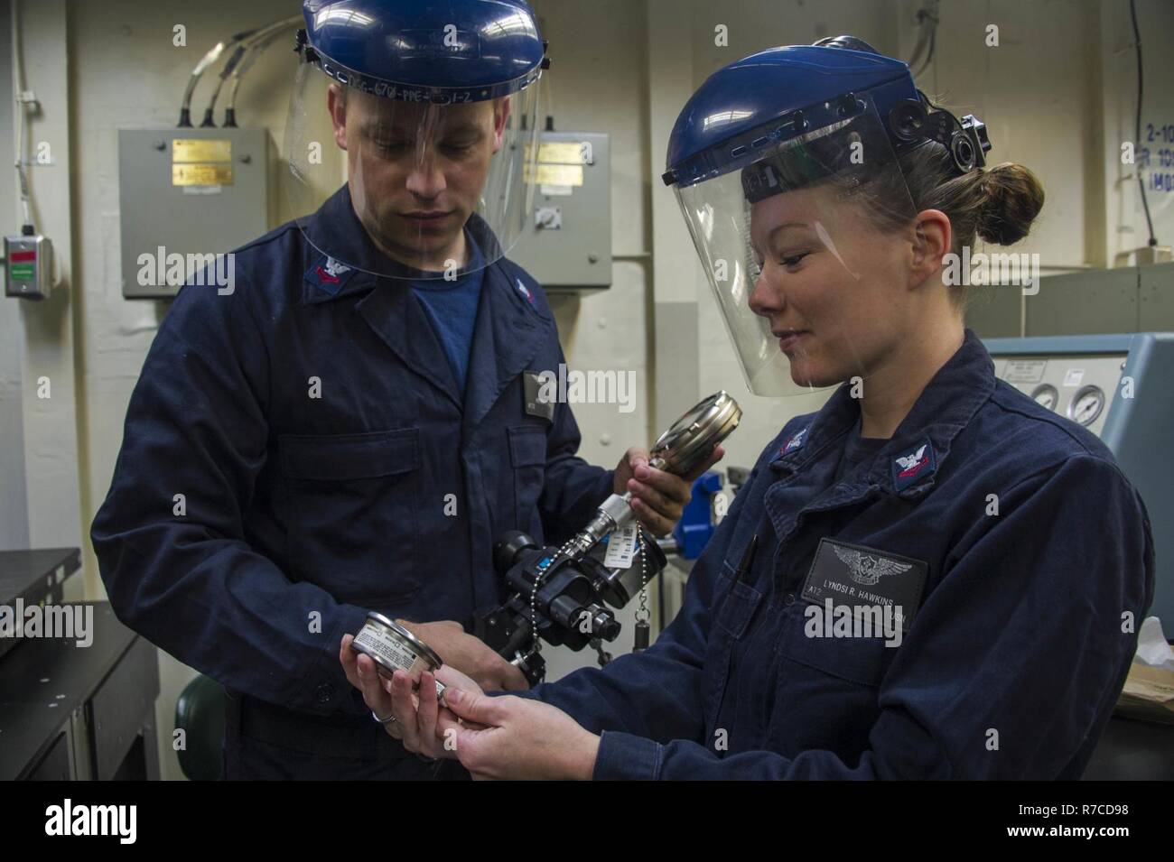 PACIFIC OCEAN (May 13, 2017) Aviation Electronics Technician 2nd Class Lyndsi Hawkins, a native of Fulton, Missouri and Aviation Electronics Technician 2nd Class Peter Wallace, a native of Webster, Massachusetts calibrate a pressure gage in the calibration lab aboard the amphibious assault ship USS America (LHA 6). More than 1,800 Sailors and 2,600 Marines assigned to the America Amphibious Ready Group (ARG) and the 15th Marine Expeditionary Unit are currently conducting a Composite Training Unit Exercise (COMPTUEX) off the coast of Southern California in preparation for the ARG's deployment l Stock Photo