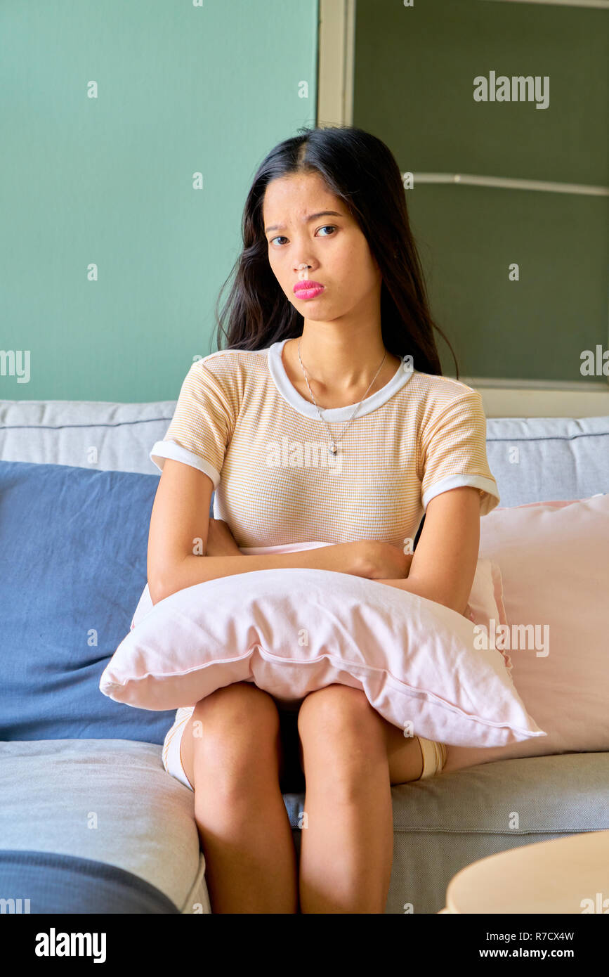Beautiful woman posing - sitting in sofa, sulking and unhappy Stock Photo