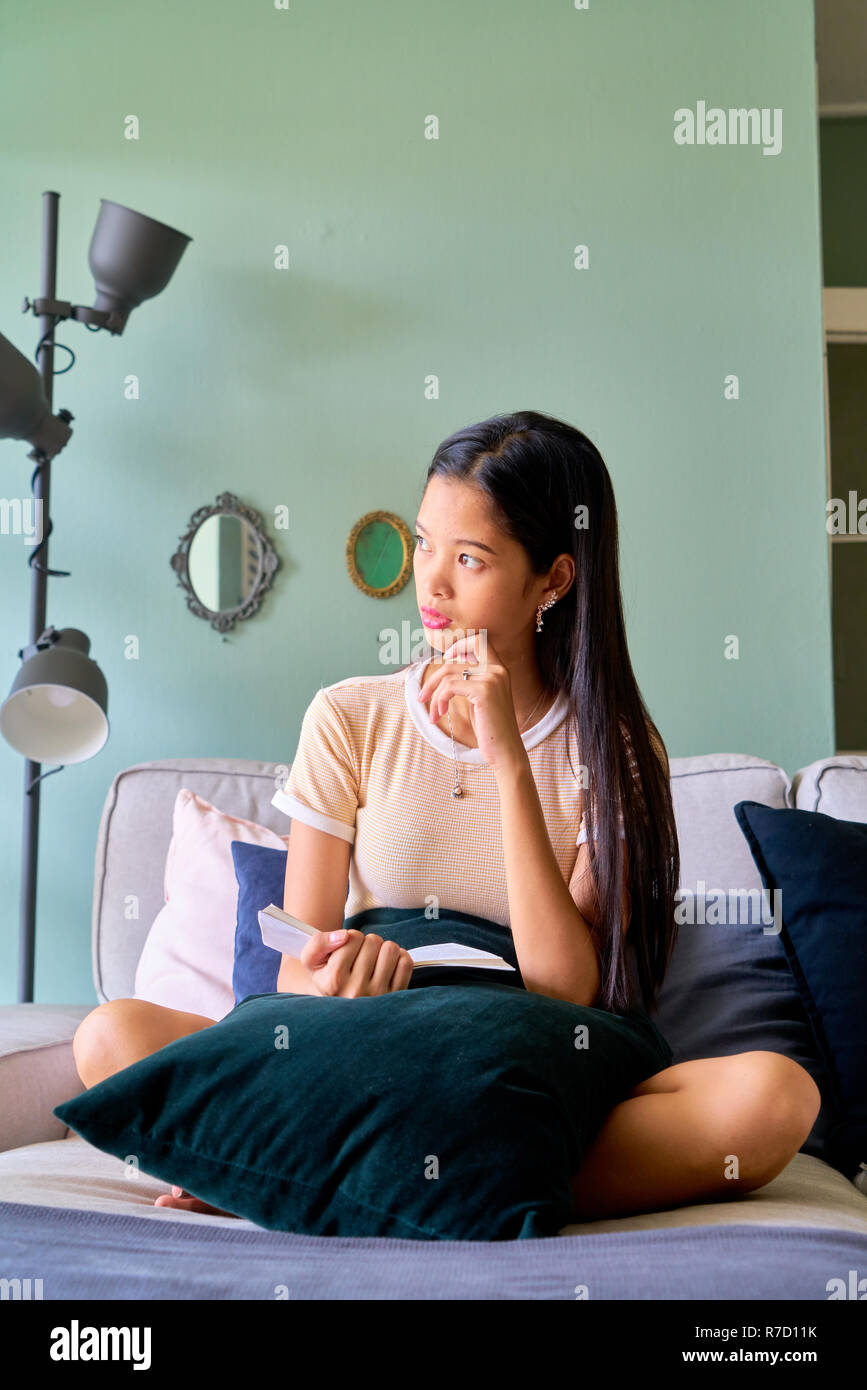 Beautiful woman posing - sitting, cross legged and thinking Stock Photo