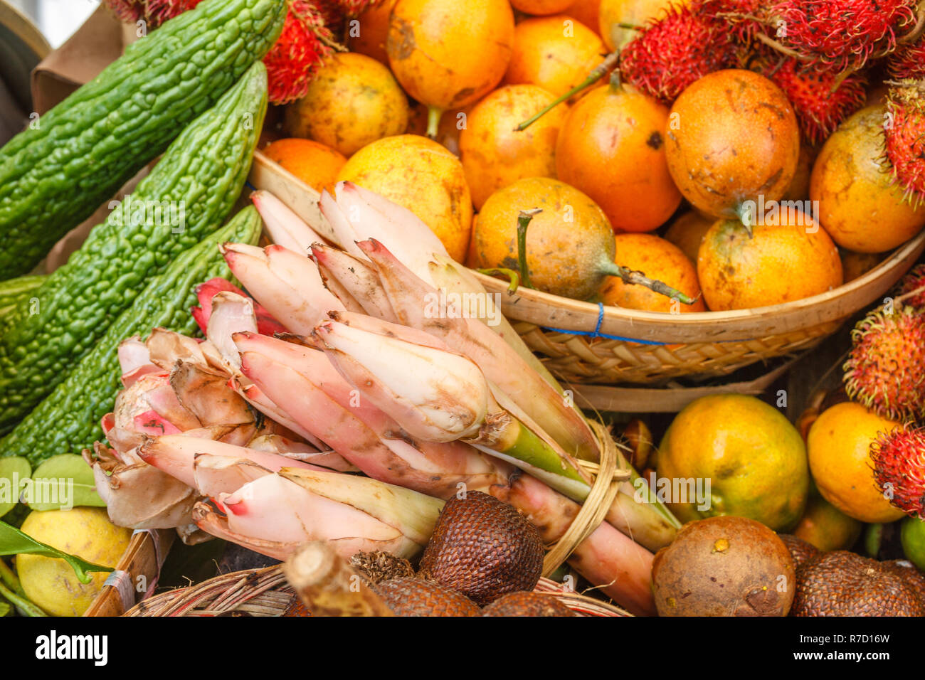 Yellow passion fruit, rambutans and banana flowers at a traditional farmers market, Bali, Indonesia. Stock Photo