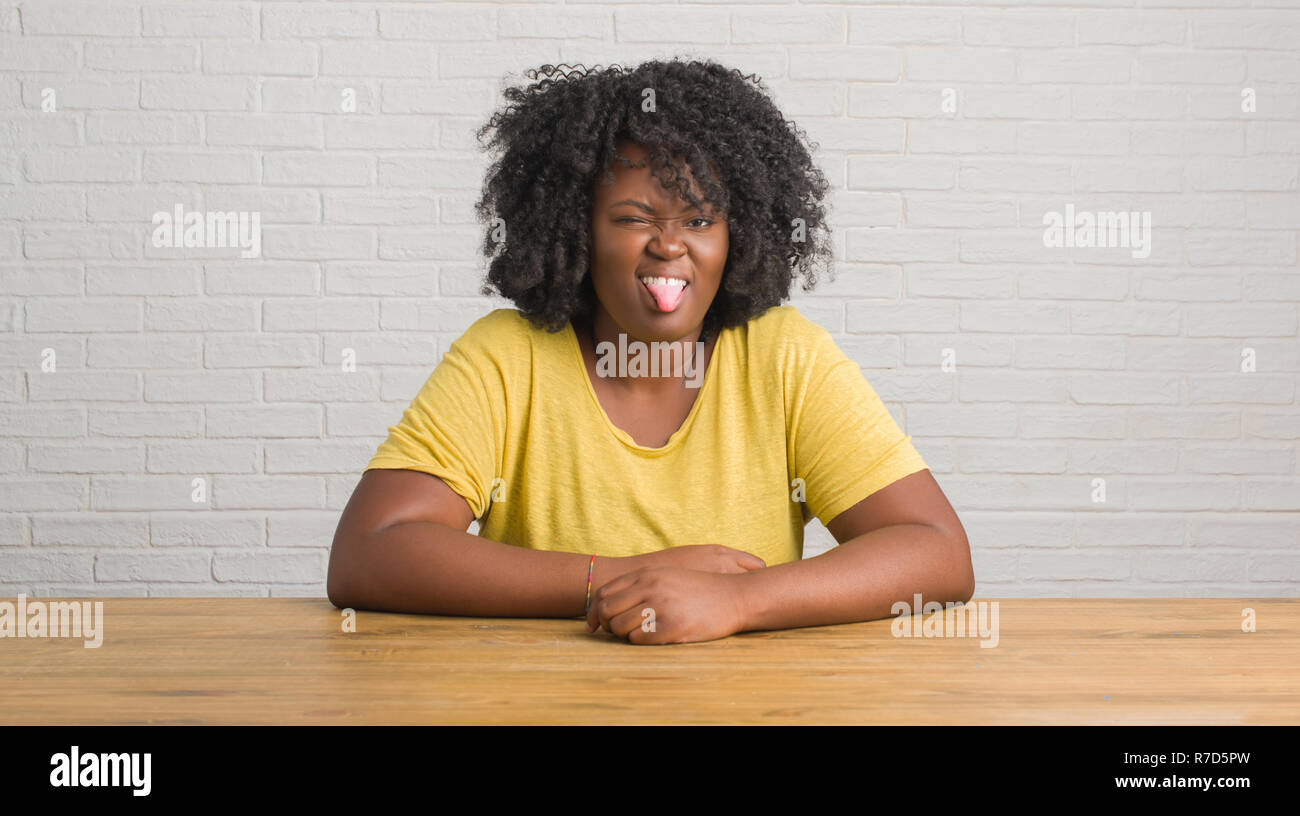 Young african american woman sitting on the table at home sticking ...