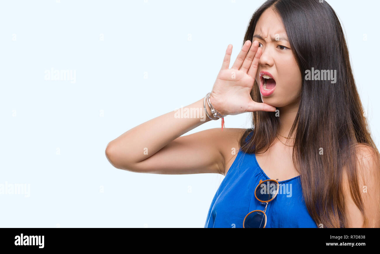 Young asian woman over isolated background shouting and screaming loud ...