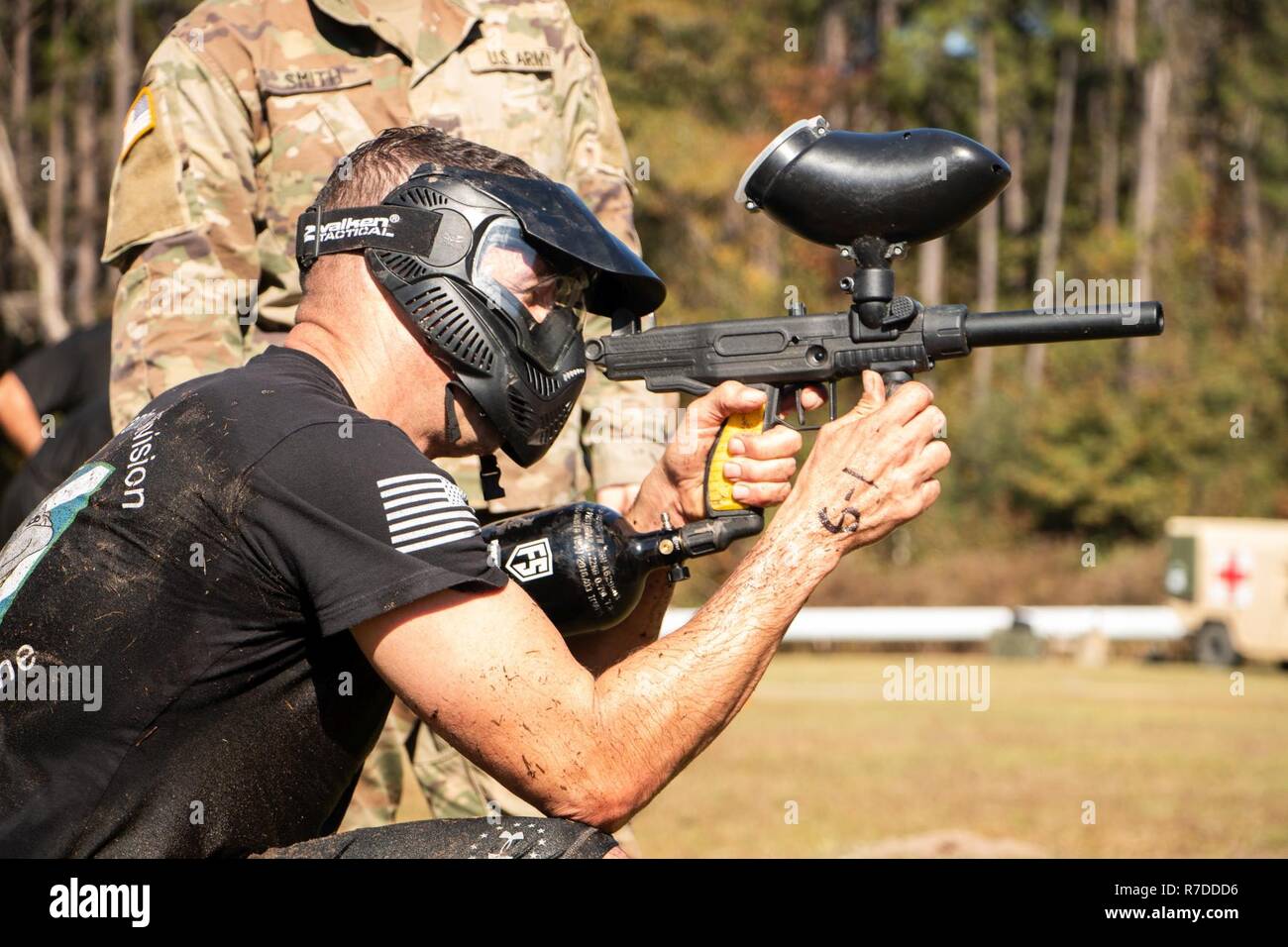 Soldier fires paintball weapon at the Marne Mudder obstacle course during Marne Week at Fort