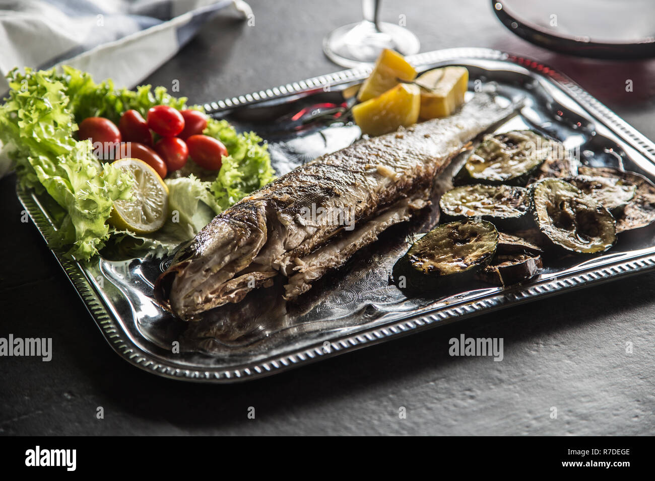 Roasted fish on dish with fresh and grilled vegetable. Stock Photo